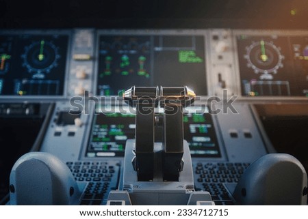 Close-up of cockpit of commercial airplane. Selective focus on engine thrust levers against illuminated control panel of modern plane.
