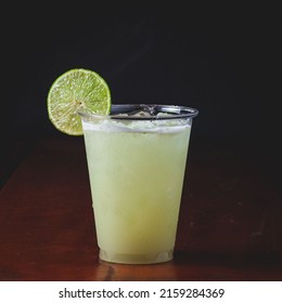 A closeup of a cocktail in a plastic cup with a lime slice - Powered by Shutterstock