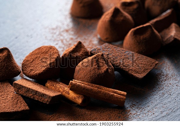 Close-up of cocoa powder, truffle chocolate and\
cinnamon on a stone\
plate