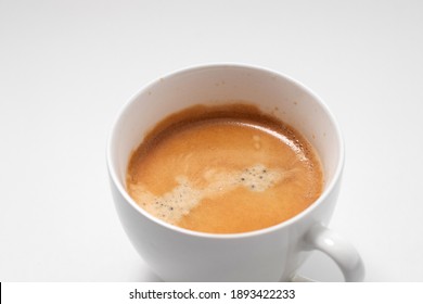 Closeup of Coffee cream on the freshly brewed coffee. Cup of cappuccino in a white mug.
