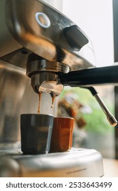 Close-up of a coffee machine making espresso with two cups in a cozy kitchen setting.