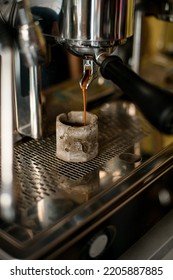 Close-up Of Coffee Machine Making Hot Drink And Which Flows Into Grey Cup Under The Metal Spout Of The Coffee Maker.