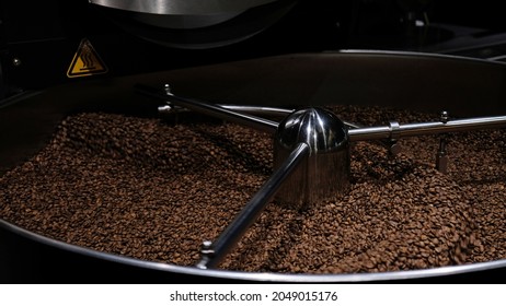 Close-up Coffee Roaster Machine At Coffee Roasting Process. Mixing Coffee Beans. Roasted Spinning Cooler Professional Machines And Fresh Brown Coffee Beans Movement Close-up Dark Photo At Factory.