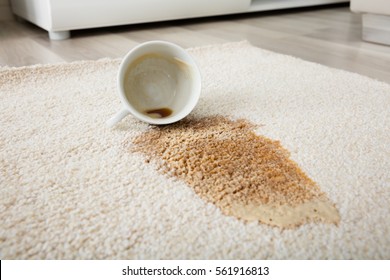 Close-up Of Coffee Spilling From Cup On Carpet