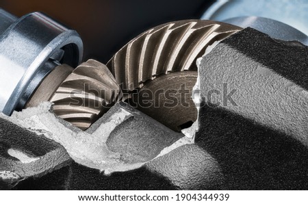 Close-up of cogged wheels inside cracked housing of side grinder engine. Steel gear mechanism detail in broken box on black background. Metal parts in damaged aluminium case. Repair. Machine-building.