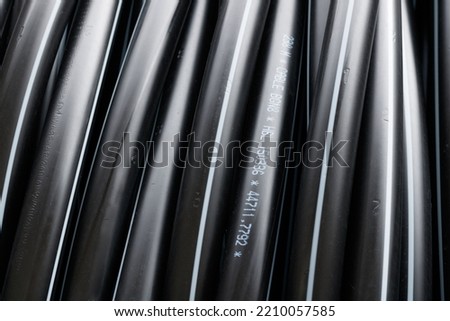 Close-up of coiled water pipes at a street construction site in Paris. The pipes are black and are about two centimeters in diameter