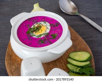 Close-up of cold chlodnik soup on a wooden board. Soup of Polish Belarusian and Russian cuisine made of beetroot and kefir, decorated with half an egg. Healthy food