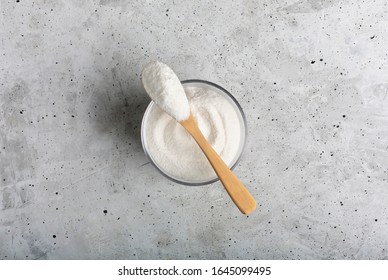 Closeup collagen in a glass with a spoon, on concrete background.