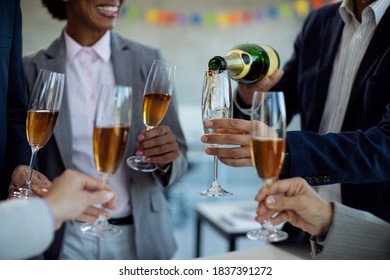 Close-up of colleagues pouring Champagne while celebrating business success on a party in the office.  - Powered by Shutterstock