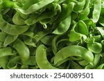 A close-up of a collection of fresh lima beans. The beans are glossy and vibrant green, showcasing their plump and smooth texture.