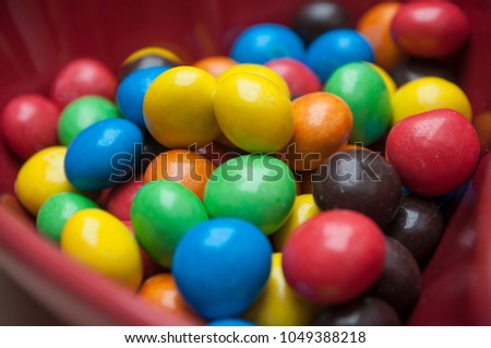closeup of colorful chocolate candies in a red bowl in shaped heart 