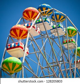 Close-up of colorful ferris wheel on vivid blue sky background