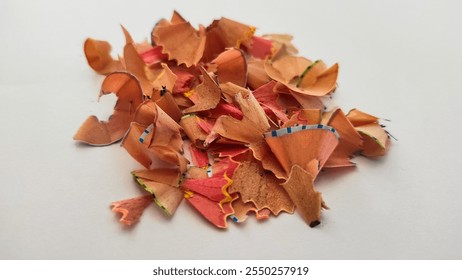 A close-up of colorful pencil shavings arranged in a pile on a clean white surface, showcasing creativity and art. - Powered by Shutterstock