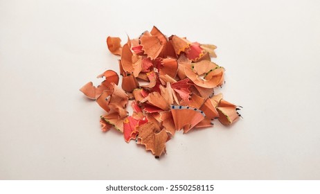 A close-up of colorful pencil shavings arranged in a pile on a clean white surface, showcasing creativity and art. - Powered by Shutterstock