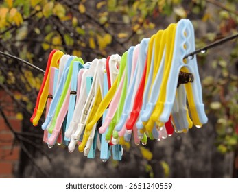 Close-up of colorful plastic clothespins clipped onto a clothesline with a blurred background. Bright and vibrant tones ideal for concept of laundry, summer, or household chores.