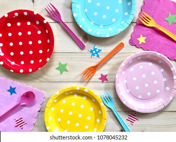 Closeup colorful polka dot paper plate,plastic fork & spoon,napkin with star on wooden background.The concept of Birthday party accessories,decoration,picnic utensil.Top view.Selective focus.