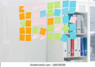 Close-up Of Colorful Sticky Notes On Glass Wall At The Office