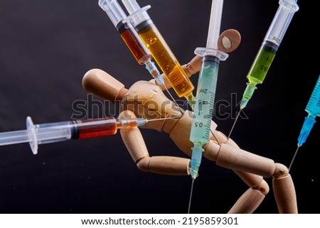 Close-up colorful syringes stucked in a wooden mannequin dummy. Drug dependence and addiction concept.