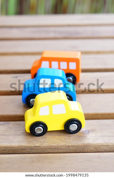 A closeup of the colorful wooden small car toys\
on the wooden surface