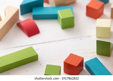 Closeup of colorful wooden toy blocks on white background wooden table. The child plays with colored cubes.