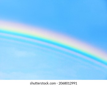 Closeup of a colourful and bright rainbow in the blue sky, space for text