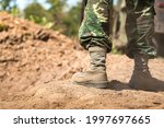 Close-up at combat shoe of a  infantryman soldier who wearied camouflage uniform during  standing on the battlefield ground. Selective focus at part of the shoe.
