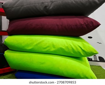 Close-up of comfortable, colorful, rectangular pillows stacked high on a faux grass carpet.