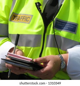 Close-up Of Community Support Police Officer Issuing Parking Tickets