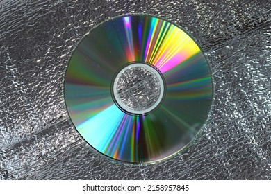 A Closeup Of A Compact Disk With Colorful Glare On A Flat Surface With Glassy Texture