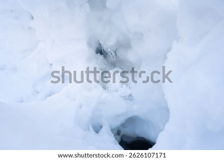 Close-up of compacted snow and ice layers forming a natural hollow. Detailed winter texture showcasing frozen structure, snow accumulation, and seasonal cold weather conditions.