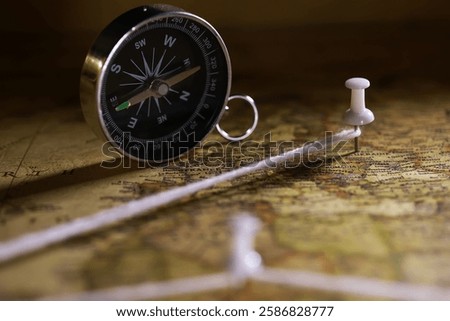Close-Up of Compass and Map with Push Pins and String for Travel Planning and Navigation