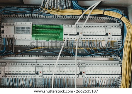 Close-up of complex electrical panel with circuit breakers, colorful wiring, and indicators during building construction