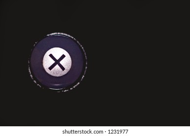 Close-up of a computer button, that has an X with reflective material surrounding it