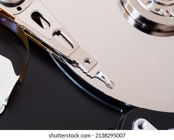 A close-up of a computer HDD hard drive disassembled, showing the actuator arm and platter disc. Concept for data storage, component hardware and technology.