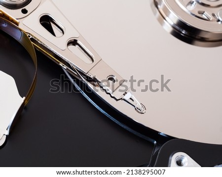 A close-up of a computer HDD hard drive disassembled, showing the actuator arm and platter disc. Concept for data storage, component hardware and technology.