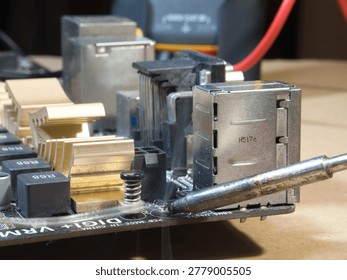 Close-up of Computer Motherboard Components; Macro shot showcasing dusty electronic components, gold heatsinks, and capacitors on a dark PC motherboard, symbolizing repair, technology, and hardware.