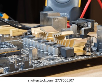 Close-up of Computer Motherboard Components; Macro shot showcasing dusty electronic components, gold heatsinks, and capacitors on a dark PC motherboard, symbolizing repair, technology, and hardware.