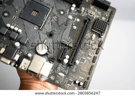 Close-up computer motherboard featuring processor socket, expansion slots and electronic circuitry, representing modern PC hardware, digital technology, electronics engineering, system upgrade and computer components.
