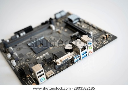 Close-up computer motherboard with processor socket and multiple input output ports, showcasing modern PC hardware, electronics, computer engineering, connectivity and digital technology on a clean background.