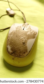 Close-up of a computer mouse with visible dirt stains attached on top of green fabric background. Concept of daily technology use, hygiene, workspace equipment, and realistic object detail suitable for microstock photography. Captured with natural lighting and detailed texture composition