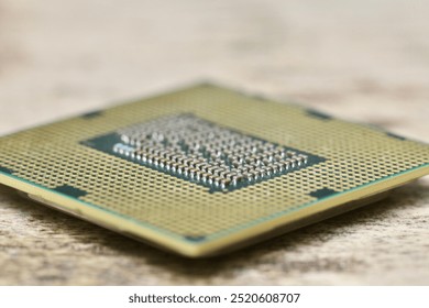 A close-up of a computer processor resting on a surface, highlighting the intricate design of the pins and the structure of the hardware. The image focuses on the fine details of modern technology