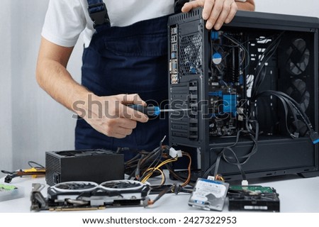 Closeup computer technician holding a screwdriver and repairing a pc
