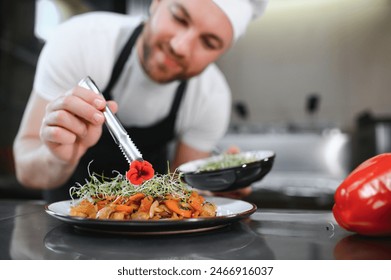 Closeup of a concentrated male chef garnishing food in the kitchen. - Powered by Shutterstock