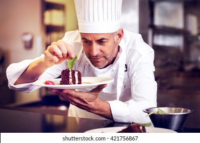 Closeup of a concentrated male pastry chef decorating dessert in the kitchen - Powered by Shutterstock