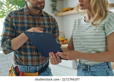 Close-up Of Confident Handyman Holding Clipboard While Woman Signing Documents