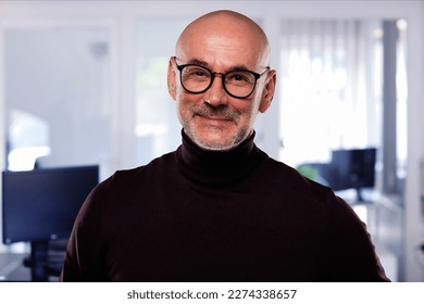 Close-up of a confident man standing at isolated grey background. Smiling businessman wearing eyewear and turtleneck sweater. - Shutterstock ID 2274338657