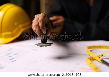 Close-up of a Construction supervision hand stamping document in the office