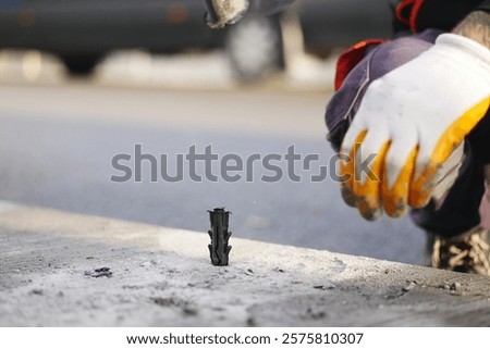 Close-Up of Construction Worker Installing Anchor Bolts in Concrete Surface