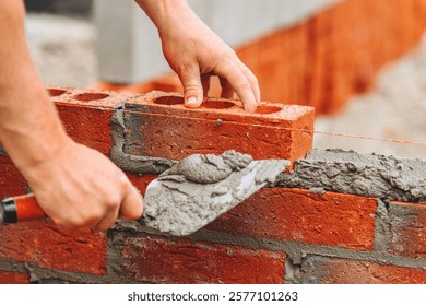 Close-up of Construction worker laying bricks with mortar during building process