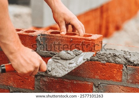 Close-up of Construction worker laying bricks with mortar during building process